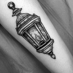 a black and white photo of a lantern tattoo on the right arm with an ink pen in it