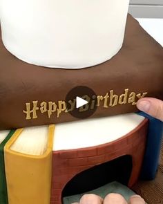 a person holding a book shaped cake with the words happy birthday on it