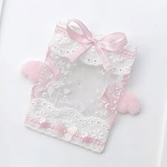 a small white box with pink bows on it's sides and lace around the edges