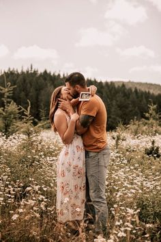 a man and woman kissing in a field with wildflowers on the other side