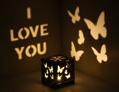 a black cube with white butterflies on it and the words i love you projected in the background