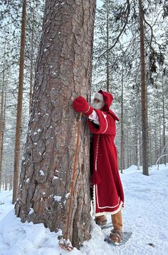 a man dressed as santa claus hugging a tree