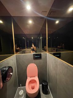 a pink toilet sitting in the middle of a bathroom next to a black trash can