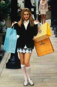 a woman holding shopping bags while walking down the street