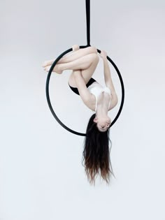 a woman is doing aerial acrobatics on a hoop