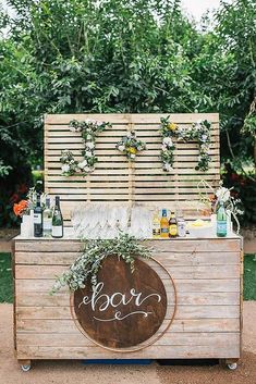 an outdoor bar is decorated with greenery and bottles