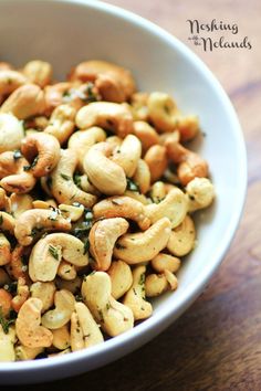 a white bowl filled with cashews on top of a wooden table