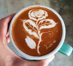 a person holding a cup of coffee with a drawing on the foam in their hand