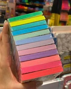 a hand holding a stack of colored erases in front of a store display case