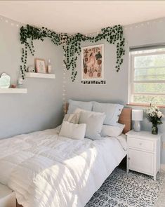 a white bed sitting in a bedroom next to a window with green vines on it