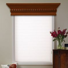 a window with white blinds and flowers in a vase next to a dresser on the floor