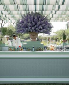 a man behind a bar with purple flowers on it