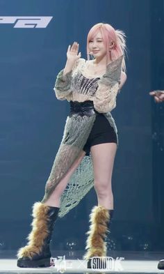 a woman with pink hair and furry boots on stage