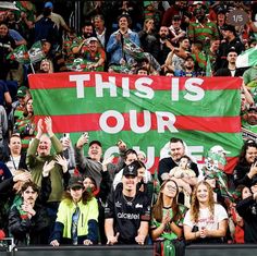 a group of people holding up a large flag in front of a crowd at a sporting event