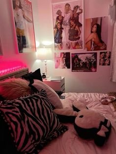 a bedroom with pink lights and pictures on the wall above the bed, along with stuffed animals