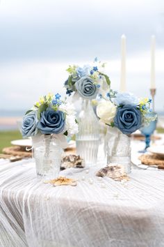 blue and white flowers are in vases on a table