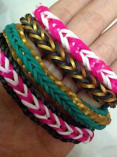 four different colored braided bracelets on someone's hand