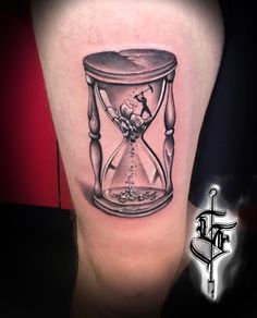 a tattoo with an hourglass on the side of its leg, which is filled with sand