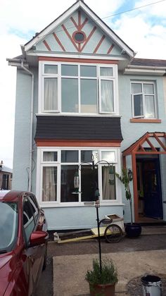 a car parked in front of a blue house with white windows and trimmings