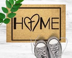 a pair of gray sneakers sitting on top of a door mat next to a plant