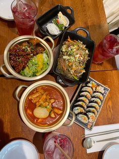 a wooden table topped with lots of different types of food and drink glasses on top of it