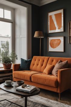 a living room with an orange couch, coffee table and two pictures on the wall