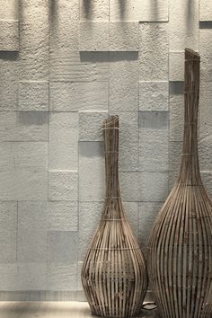 two vases sitting next to each other in front of a white wall with vertical lines on it