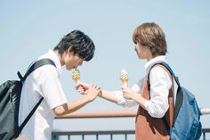 two people standing next to each other holding ice cream cones in their hands and looking at each other