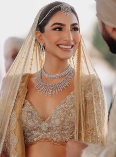 the bride smiles as she is dressed in her bridal gown and veil with jewels on it