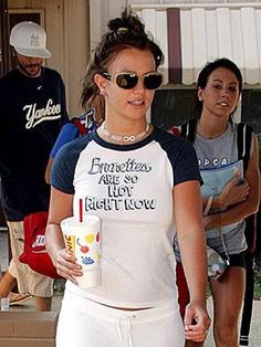 a woman walking down the street with a drink in her hand and two other people behind her