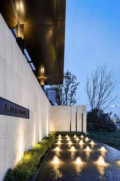 the entrance to an office building with lights on it's sides and grass growing in front