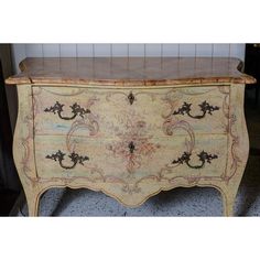 an old dresser with marble top and gold paint on it's drawers, in the corner of a room