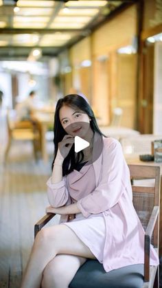 a woman sitting on top of a wooden chair next to a table in a building