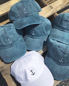 five hats with an anchor on them sitting on top of a wooden bench next to each other