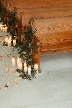 candles are lined up on the ground in front of pews