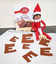 an elf sitting on top of a table next to a box of brownie cake