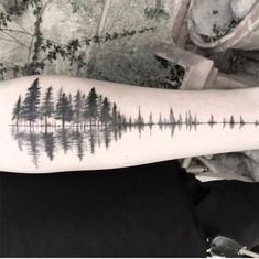 a person with a tattoo on their arm that has trees in the water and sound waves