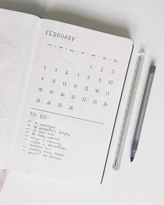 an open notebook with a calendar and pen next to it