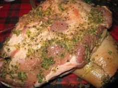 a piece of meat covered in herbs and seasoning sitting on a red table cloth