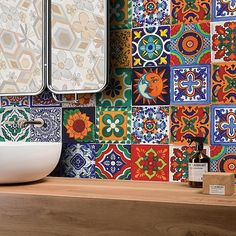 a bathroom with colorful tiles on the wall and counter top, along with a white sink