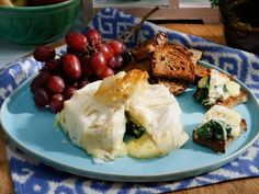 a blue plate topped with food next to grapes and bread