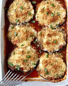 baked eggplant parmesan in a white casserole dish with a fork