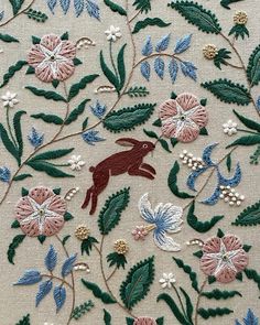 an embroidered design with flowers, leaves and a rabbit on it's back side