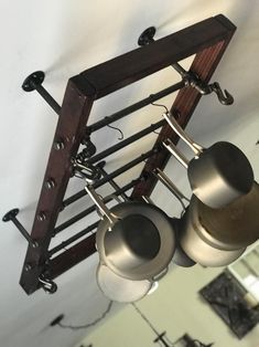 three metal pots and pans are hanging from a rack in a kitchen with white walls