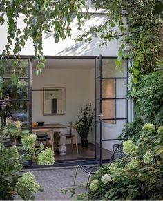 an open door leading to a dining room and patio area with plants on either side