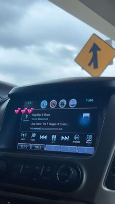 a car dashboard with an arrow on the screen and a road sign in the background