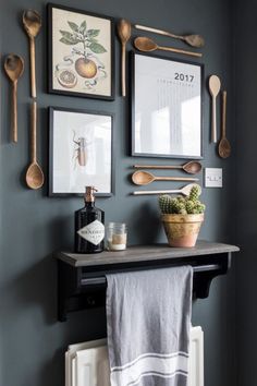 a kitchen wall with spoons, utensils and pictures on the wall above it