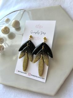 black and gold glittered earrings on top of a card