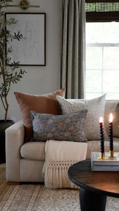 a living room with a couch, coffee table and two candles on top of it