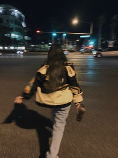 a woman walking across a street at night